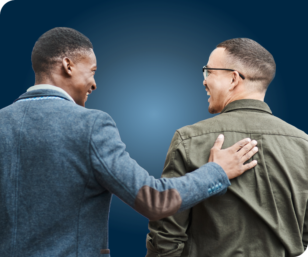 Back image of two men smiling at one another, with one patting the back of the other